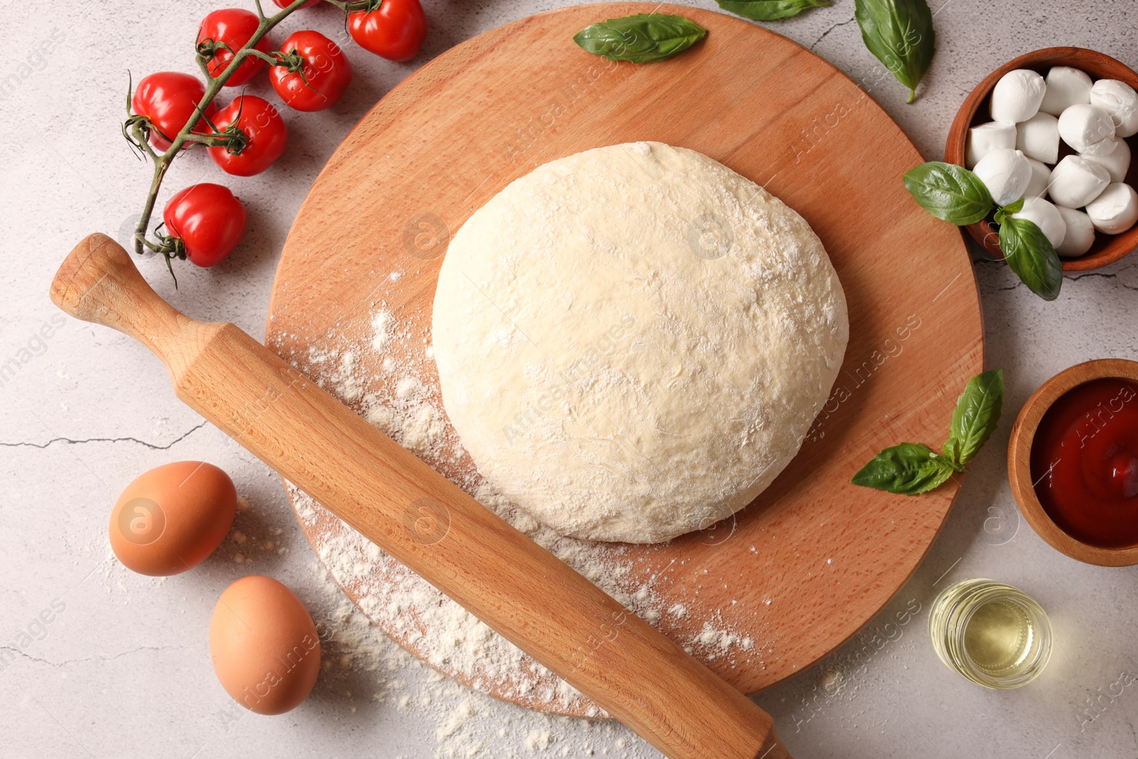 Photo of Pizza dough, products and rolling pin on gray textured table, flat lay