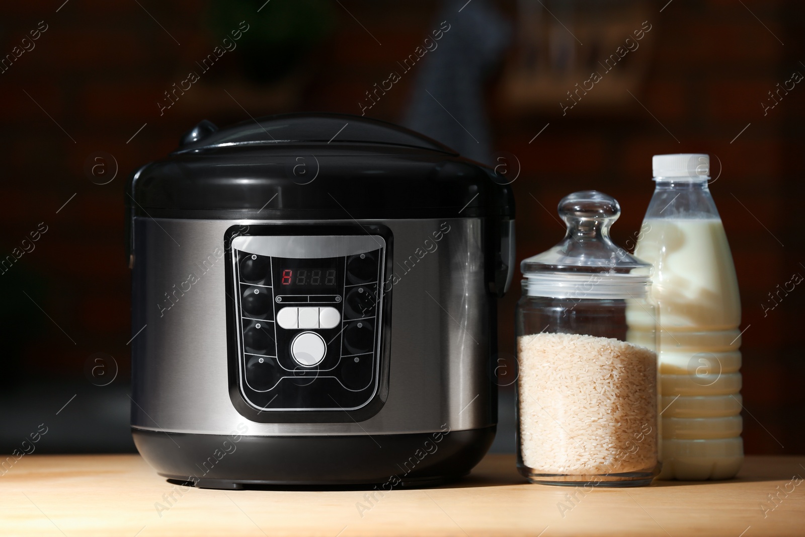 Photo of Modern electric multi cooker, rice and milk on table in kitchen