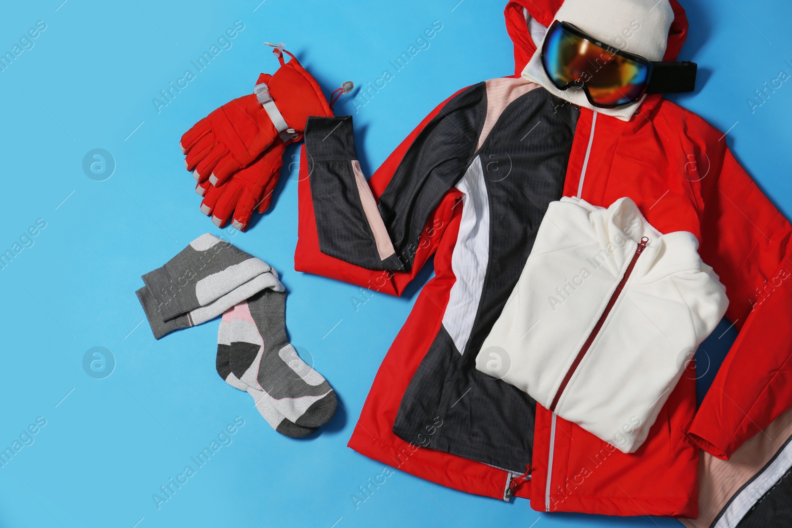 Photo of Stylish winter sport clothes on light blue background, flat lay