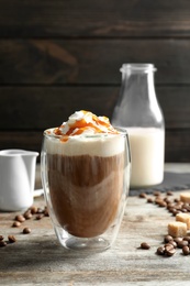 Glass of coffee with caramel topping on wooden table