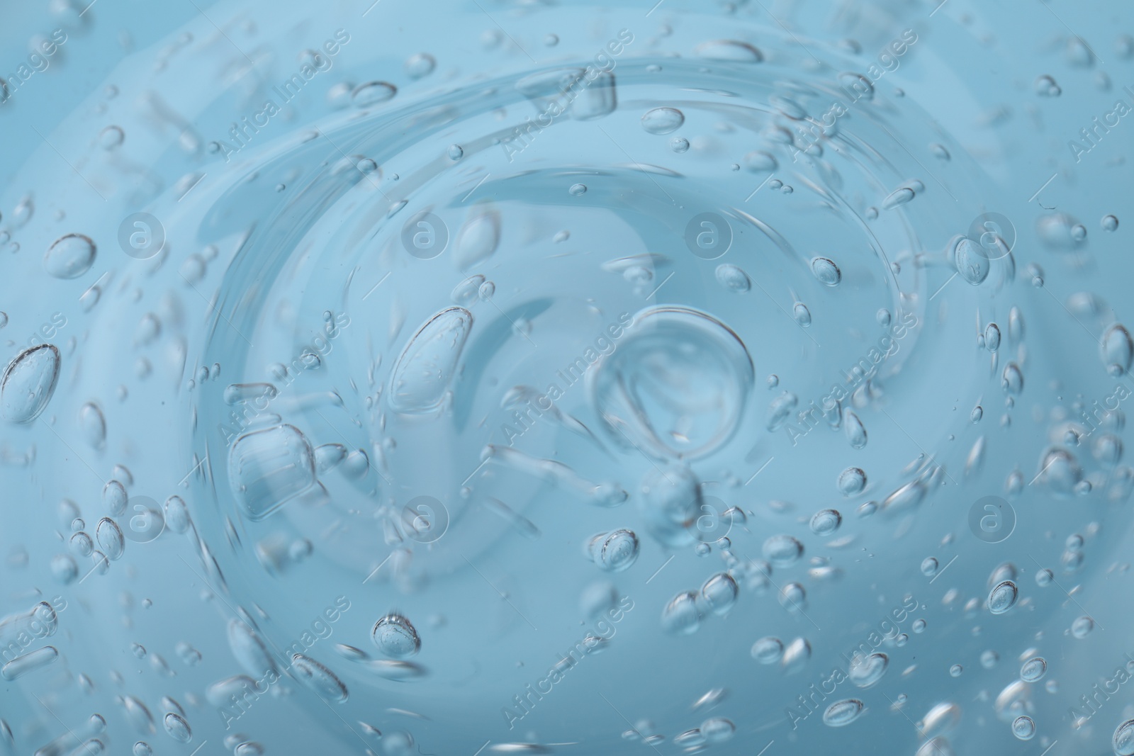 Photo of Pure transparent cosmetic gel on light blue background, closeup