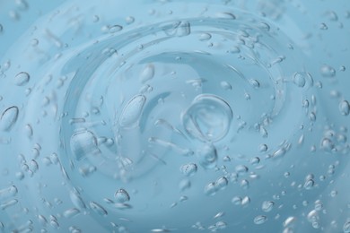 Photo of Pure transparent cosmetic gel on light blue background, closeup