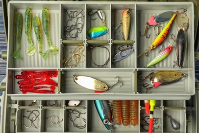 Box with different fishing accessories as background, top view