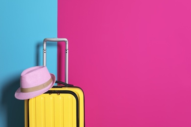 Photo of Bright yellow suitcase with hat on color background