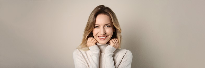 Image of Portrait of happy young woman with beautiful blonde hair and charming smile on beige background. Horizontal banner design