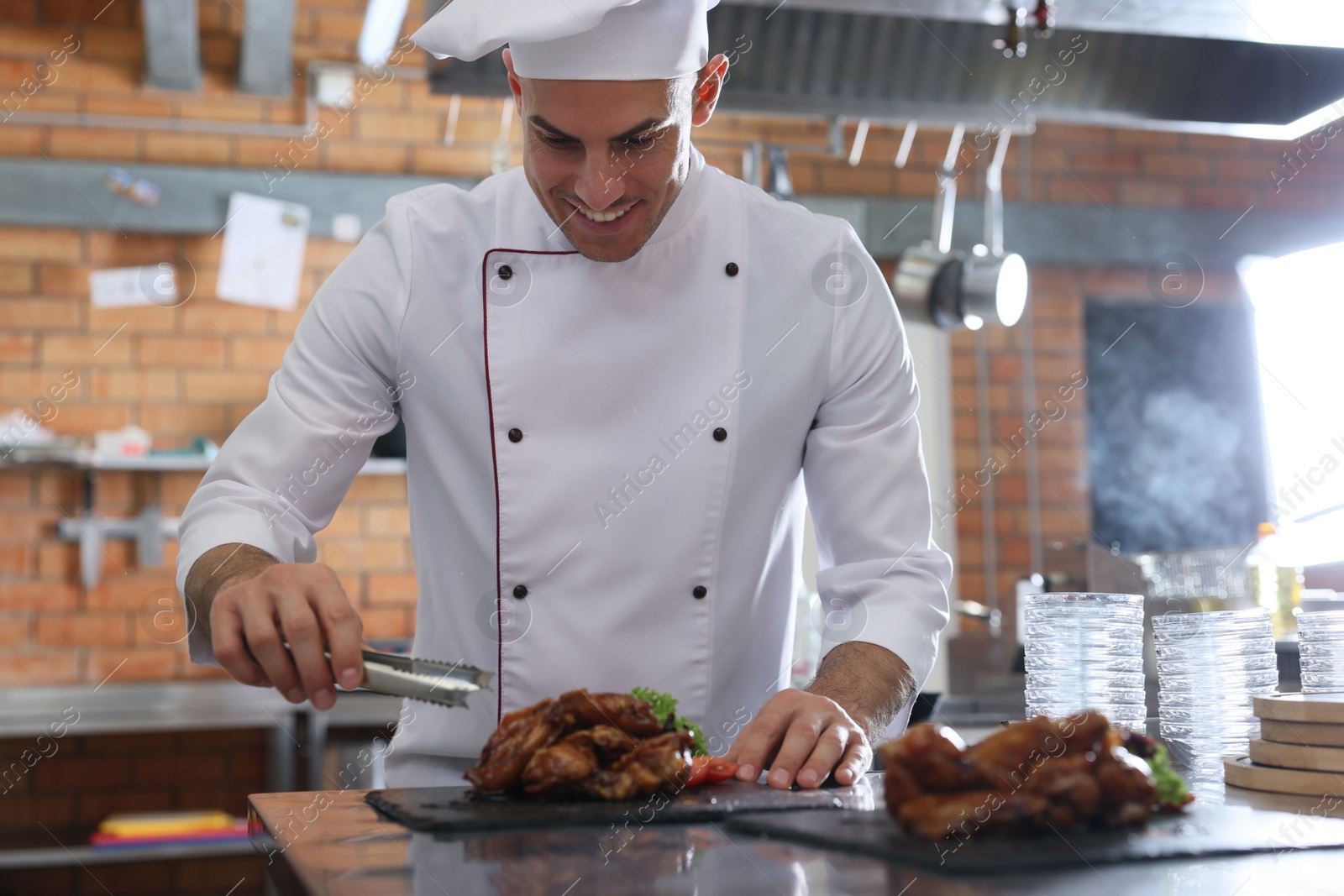 Photo of Professional chef with delicious fried chicken wings in restaurant kitchen
