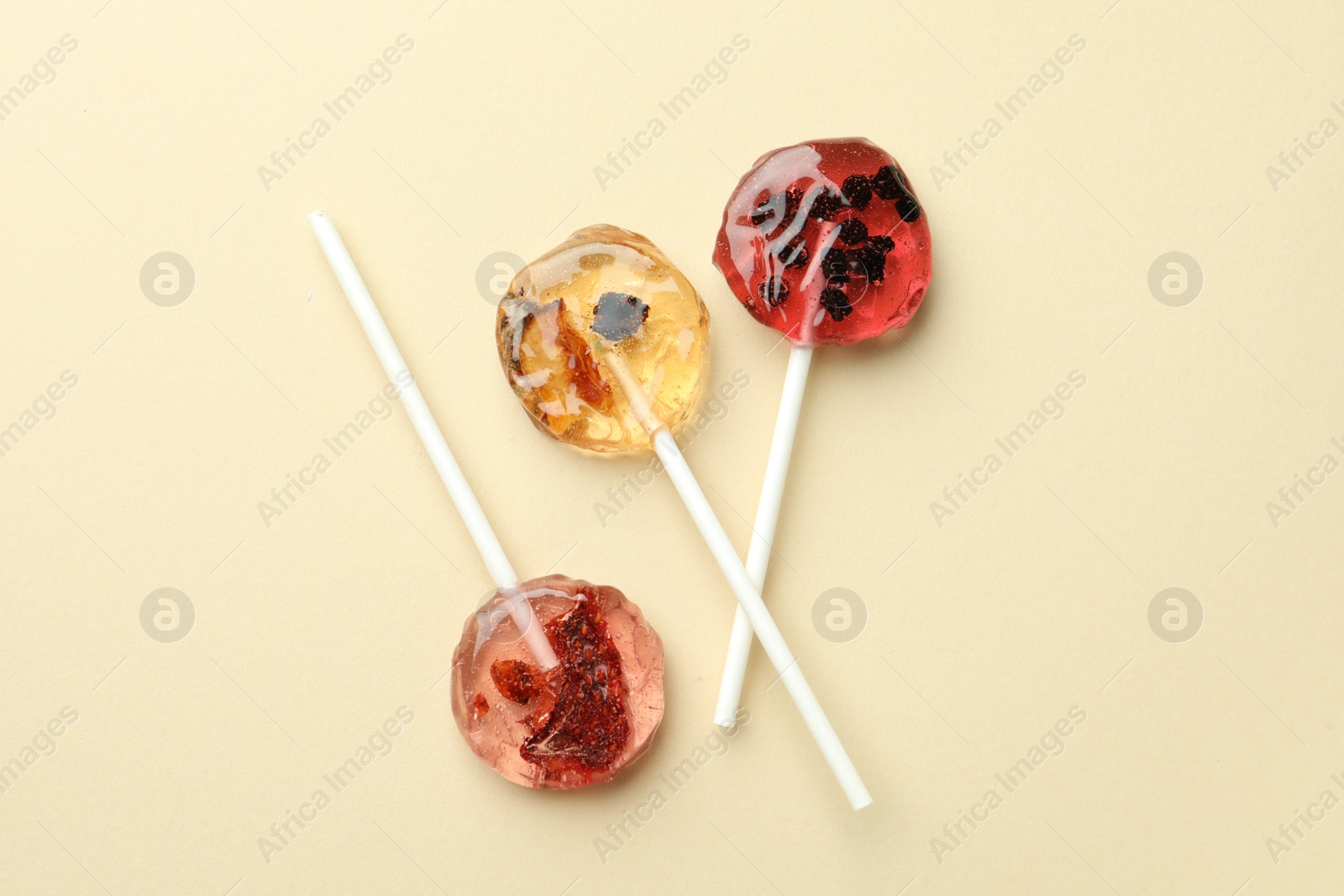 Photo of Sweet colorful lollipops with berries on beige background, flat lay