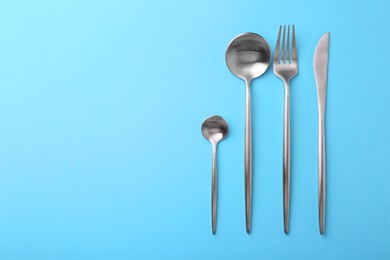 Stylish cutlery set on light blue table, flat lay. Space for text