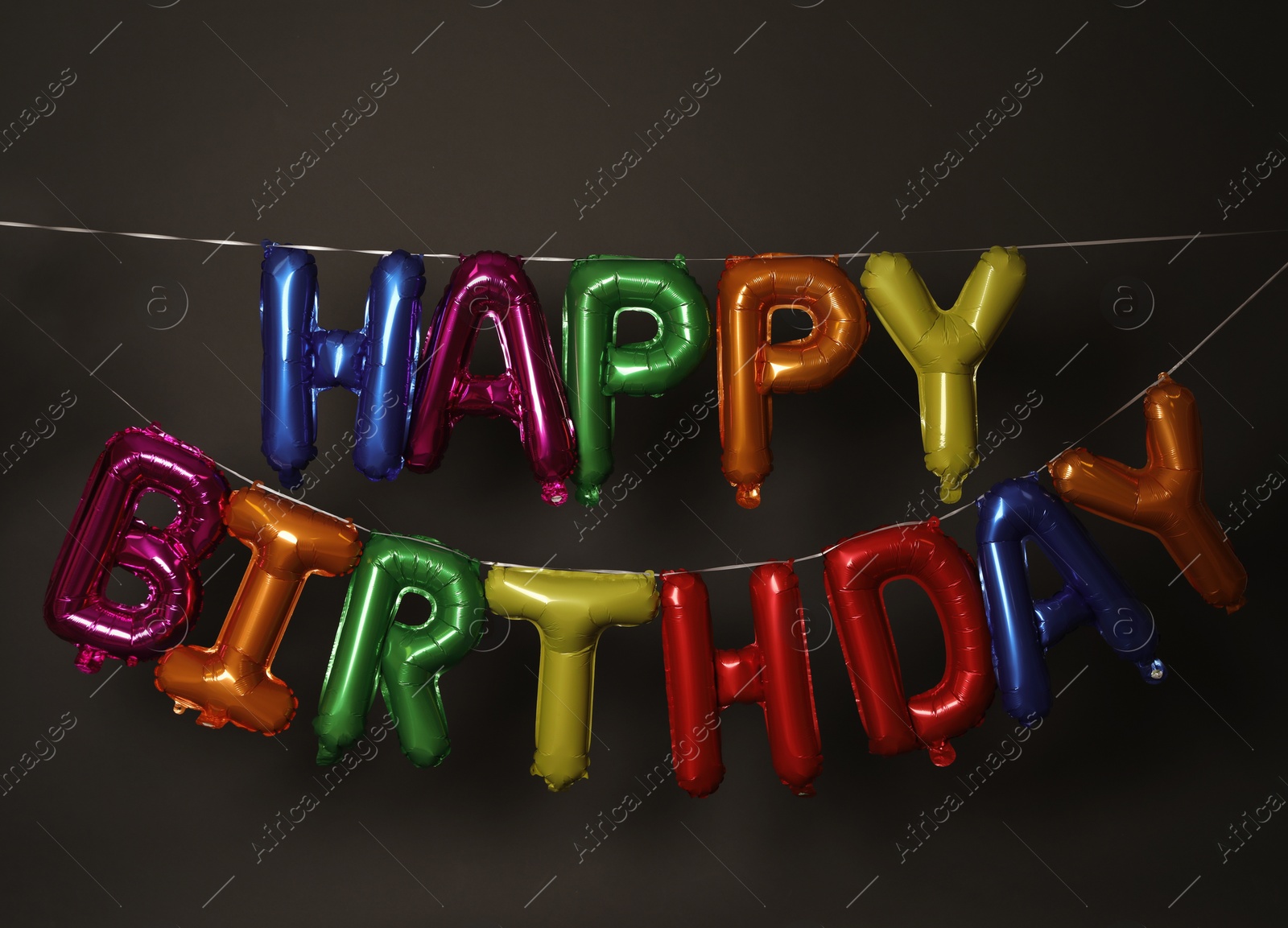 Photo of Phrase HAPPY BIRTHDAY made of colorful balloon letters on dark background