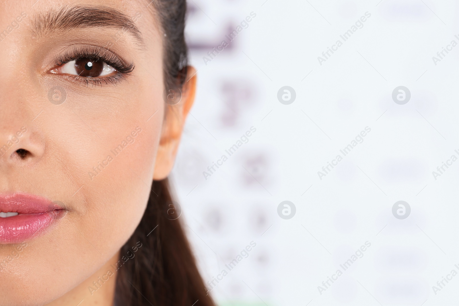 Photo of Closeup view of young woman and blurred eye chart on background. Space for text