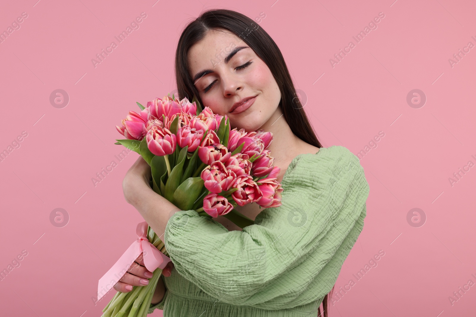 Photo of Happy young woman with beautiful bouquet on dusty pink background