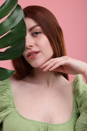 Portrait of beautiful woman with freckles and monstera leaf on pink background