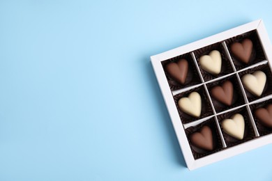 Tasty heart shaped chocolate candies on light blue background, top view with space for text. Happy Valentine's day