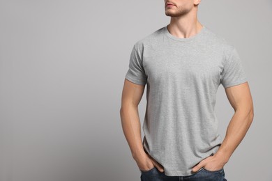 Man wearing blank t-shirt on light grey background, closeup. Mockup for design