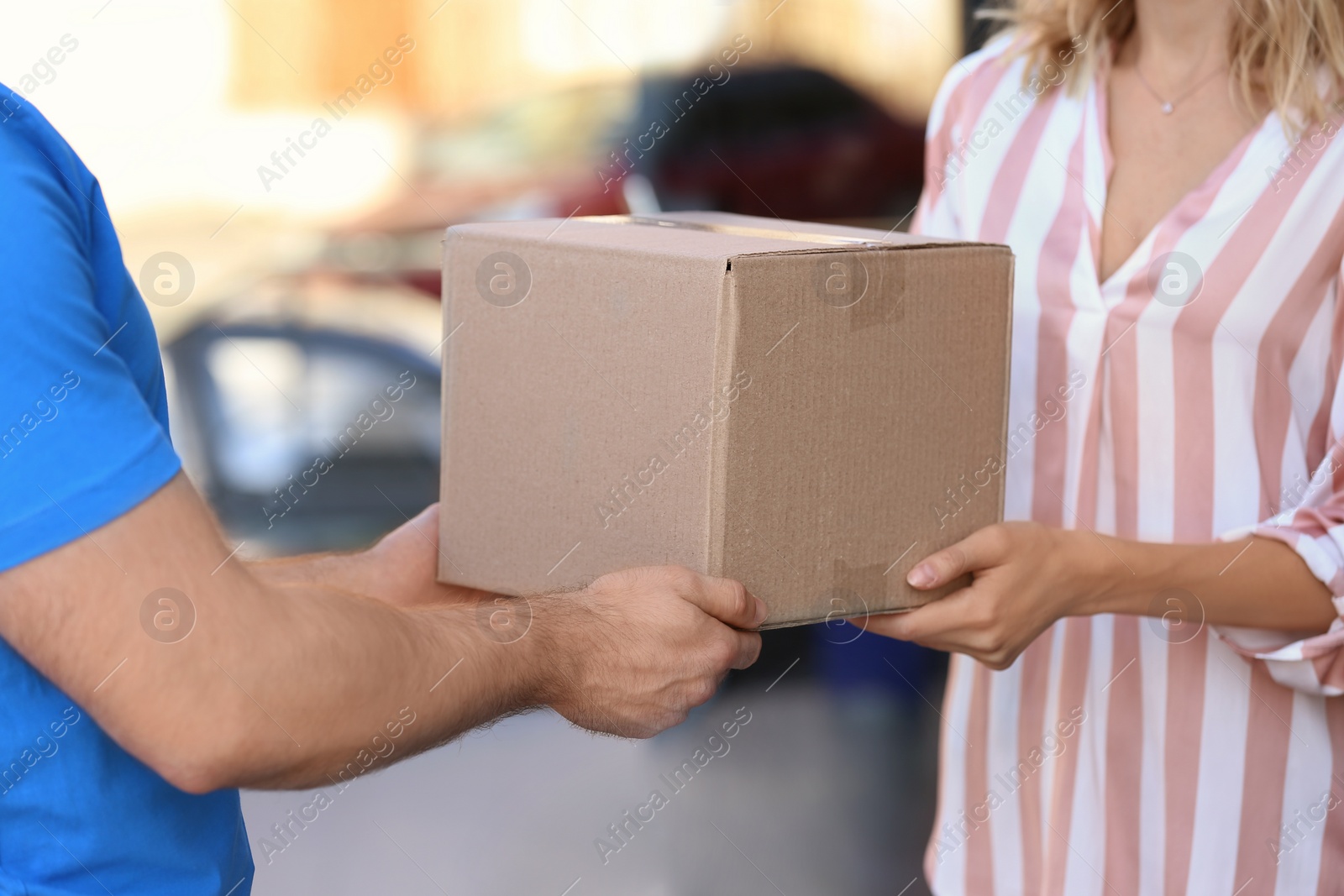 Photo of Woman receiving parcel from deliveryman on blurred background, closeup. Space for text