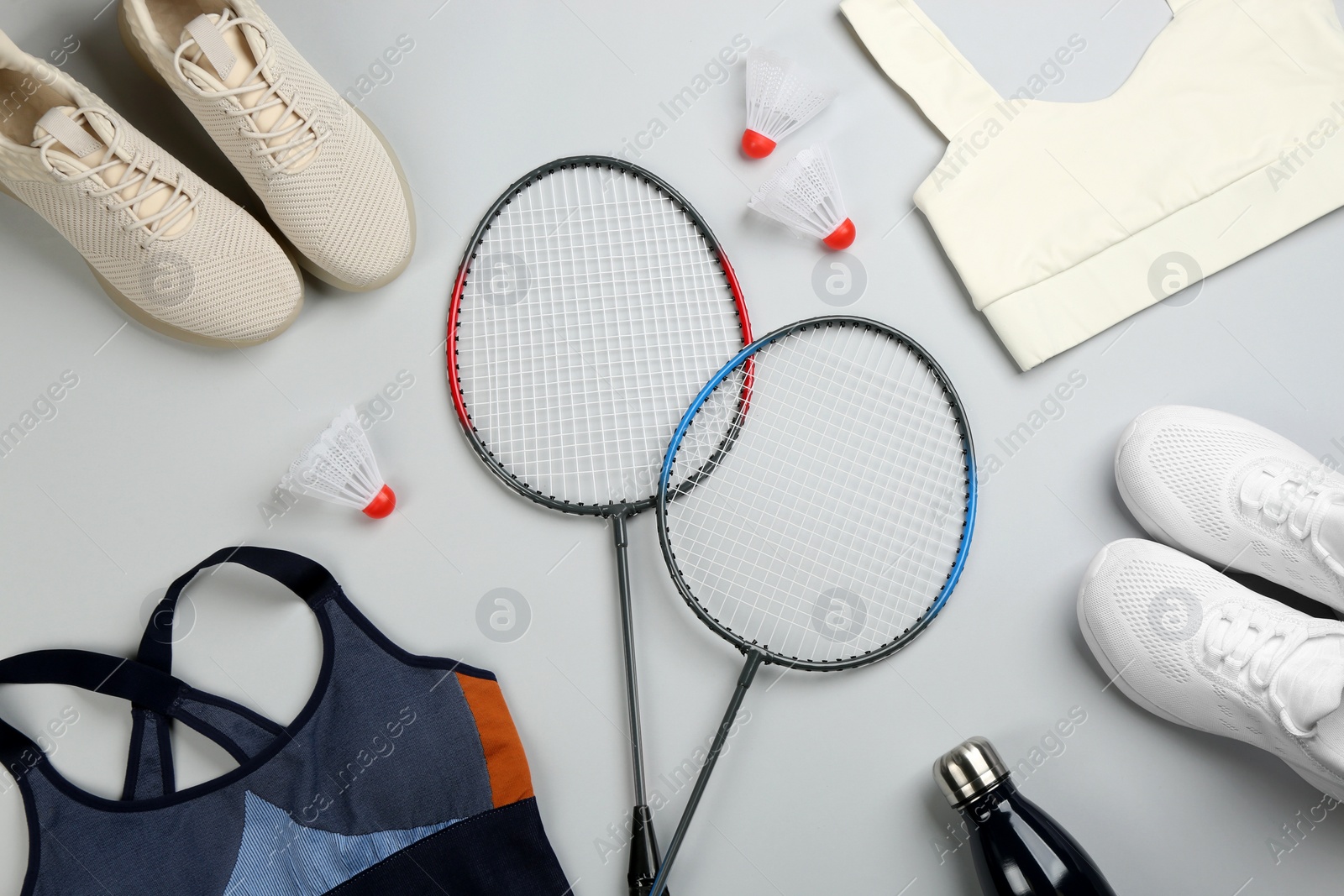 Photo of Flat lay composition with rackets and shuttlecocks on light grey background. Playing badminton