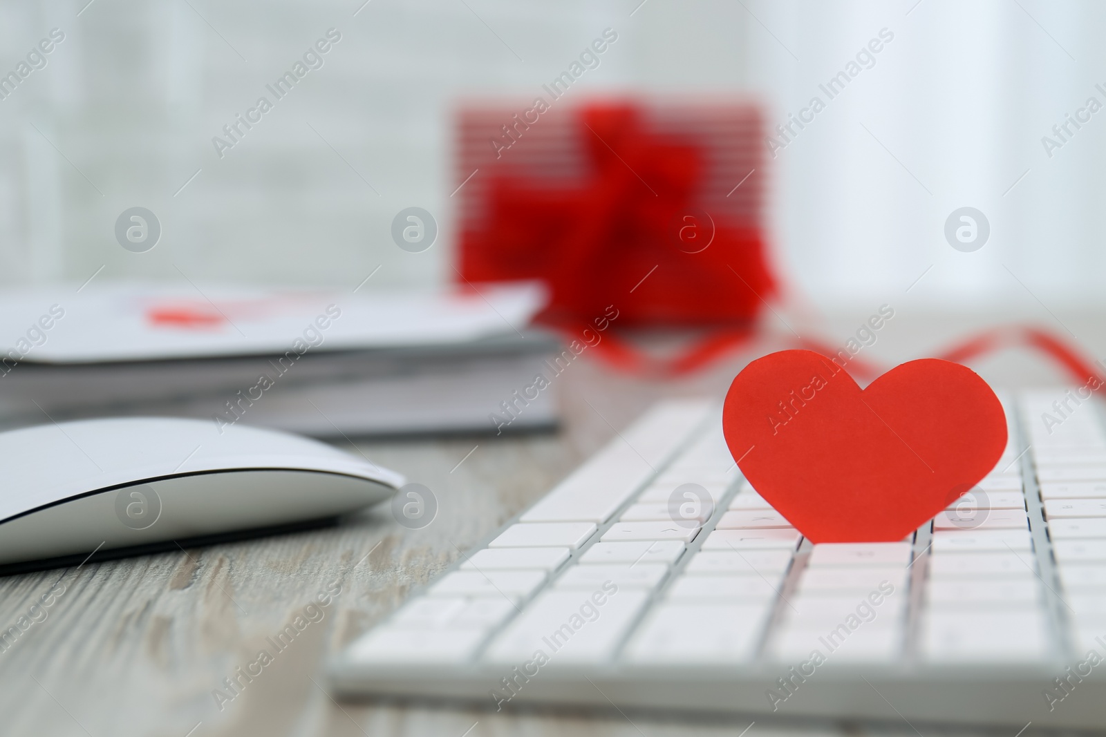 Photo of Red heart on keyboard at table, closeup with space for text. Valentine's Day celebration