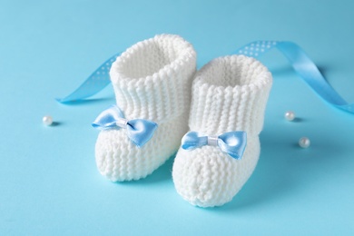Photo of Handmade baby booties with bows on color background