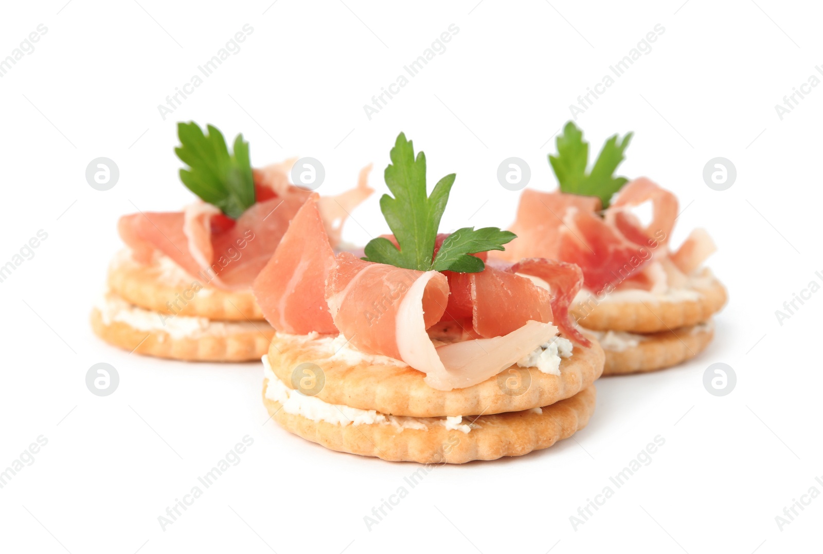 Photo of Delicious crackers with cream cheese, prosciutto and parsley on white background