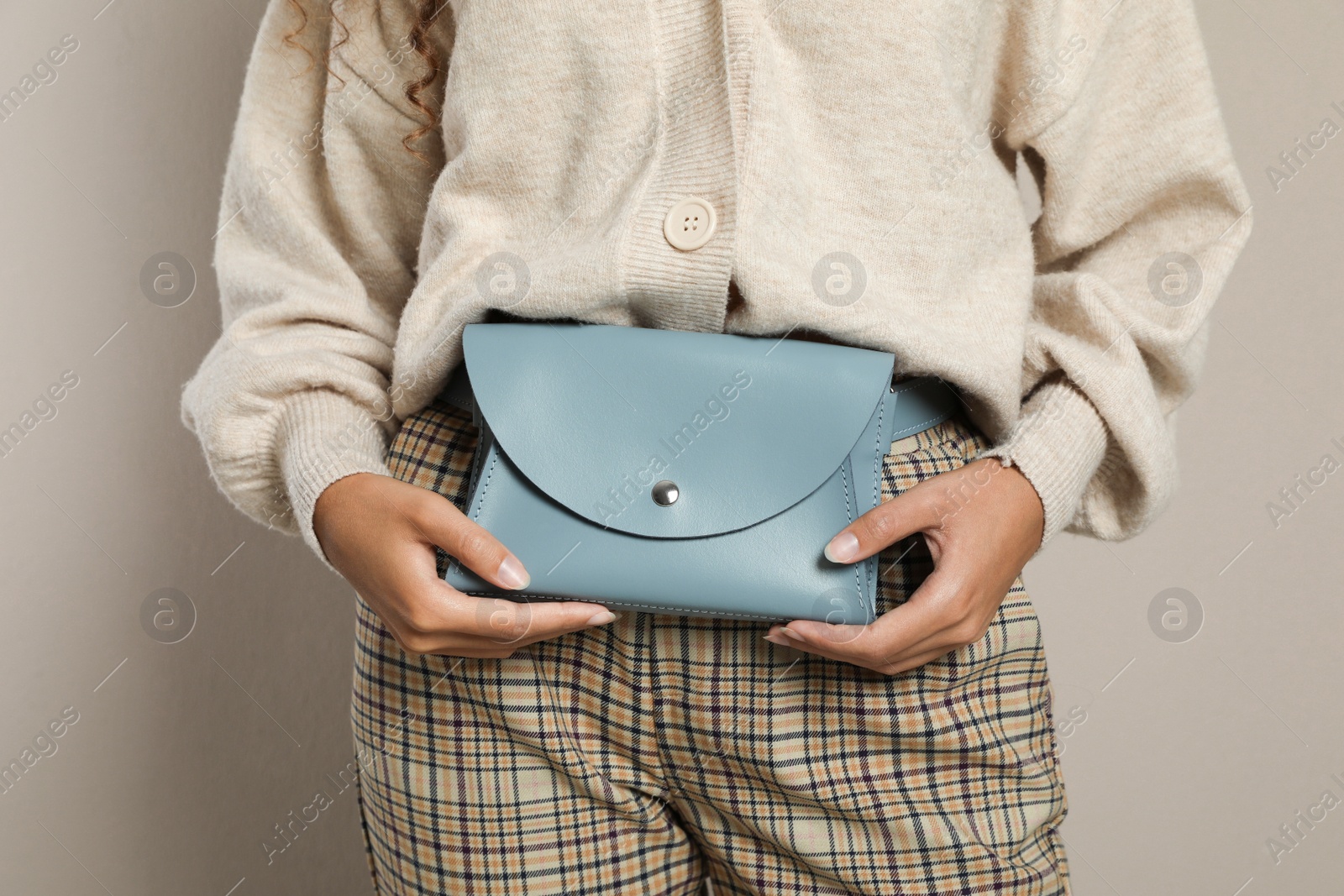 Photo of Young African American woman with stylish waist bag on beige background, closeup