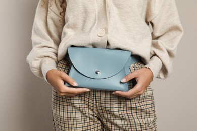 Photo of Young African American woman with stylish waist bag on beige background, closeup