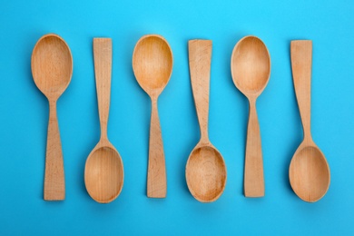 Photo of Clean empty wooden spoons on blue background, flat lay