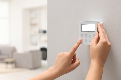 Photo of Woman adjusting thermostat on white wall indoors, closeup and space for text. Smart home system