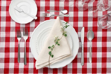 Stylish setting with cutlery, plates, napkin, glasses and floral decor on table, flat lay