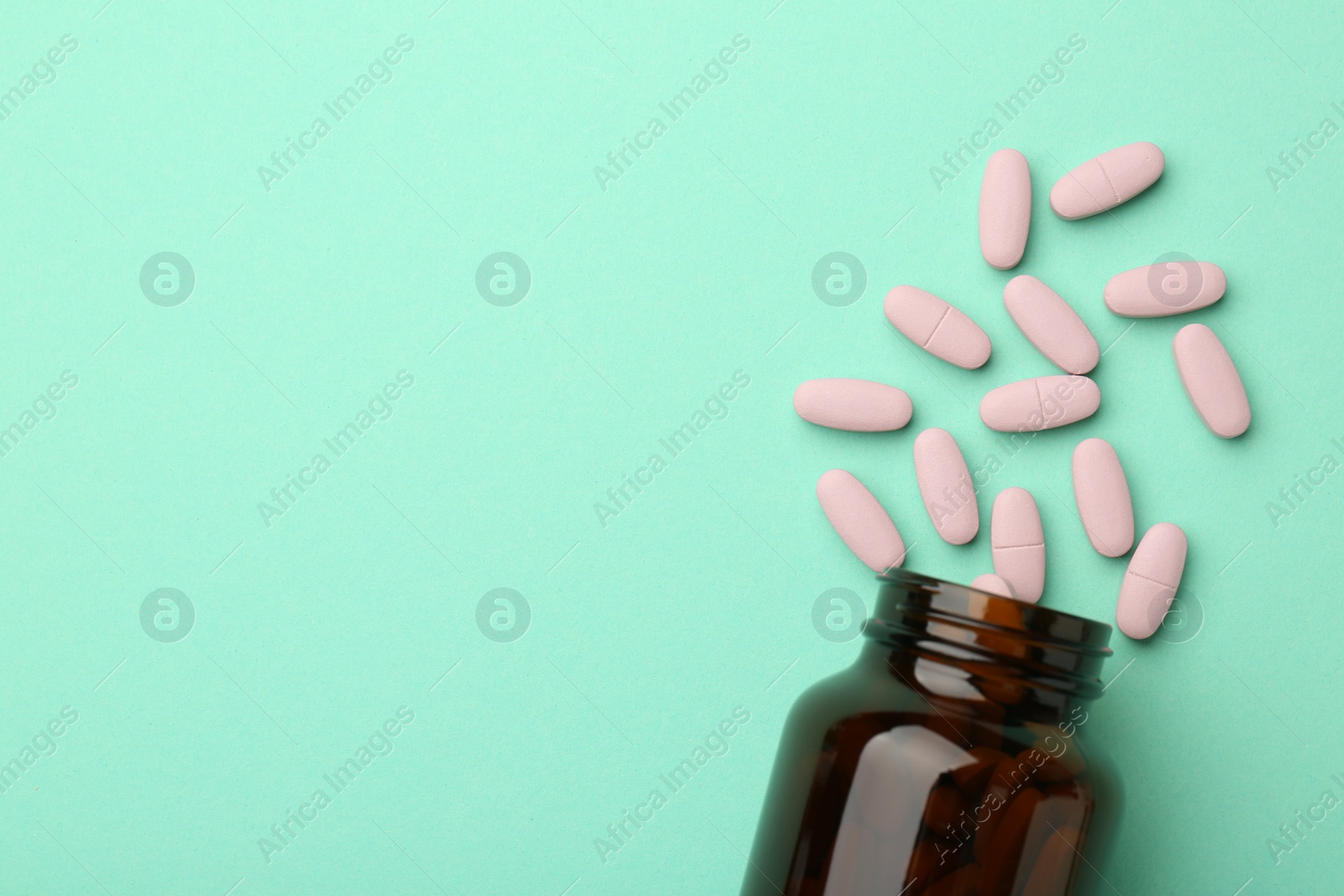 Photo of Vitamin pills and bottle on mint color background, top view. Space for text