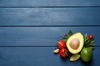 Photo of Fresh guacamole ingredients on blue wooden table, flat lay. Space for text