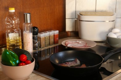 Cooking bacon in frying pan for breakfast in kitchen