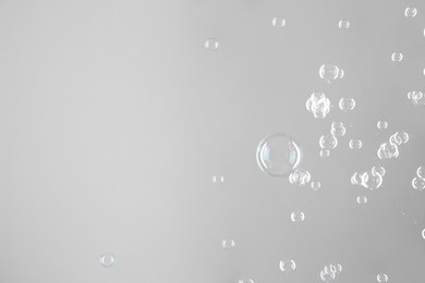 Beautiful transparent soap bubbles on grey background, space for text