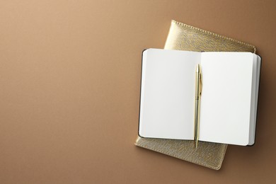 Photo of Notebooks and pen on light brown background, top view. Space for text