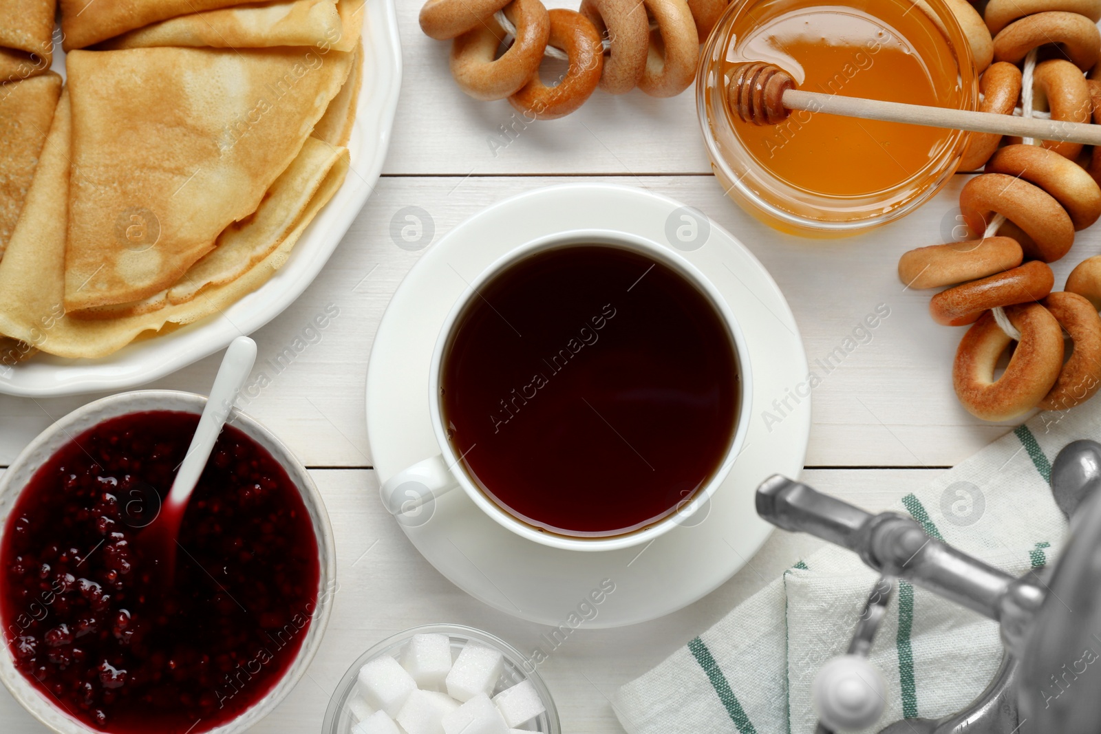 Photo of Metal samovar with cup of tea and treats on white wooden table, flat lay