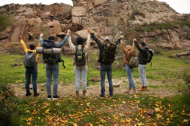 Photo of Group of hikers with backpacks in mountains, back view