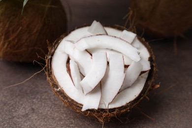 Photo of Coconut pieces in nut shell on brown table, closeup