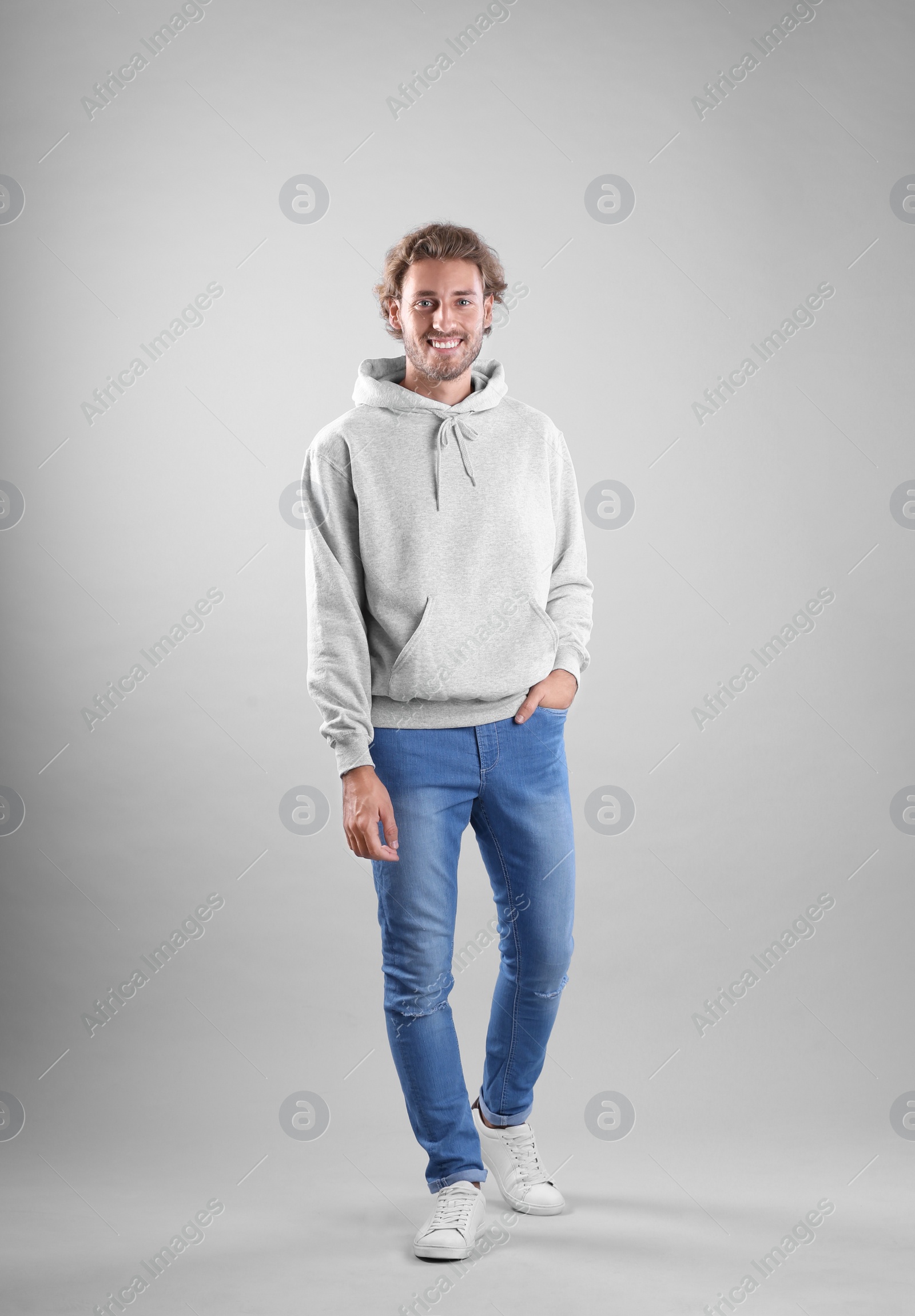 Photo of Full length portrait of man in hoodie sweater on light background. Space for design