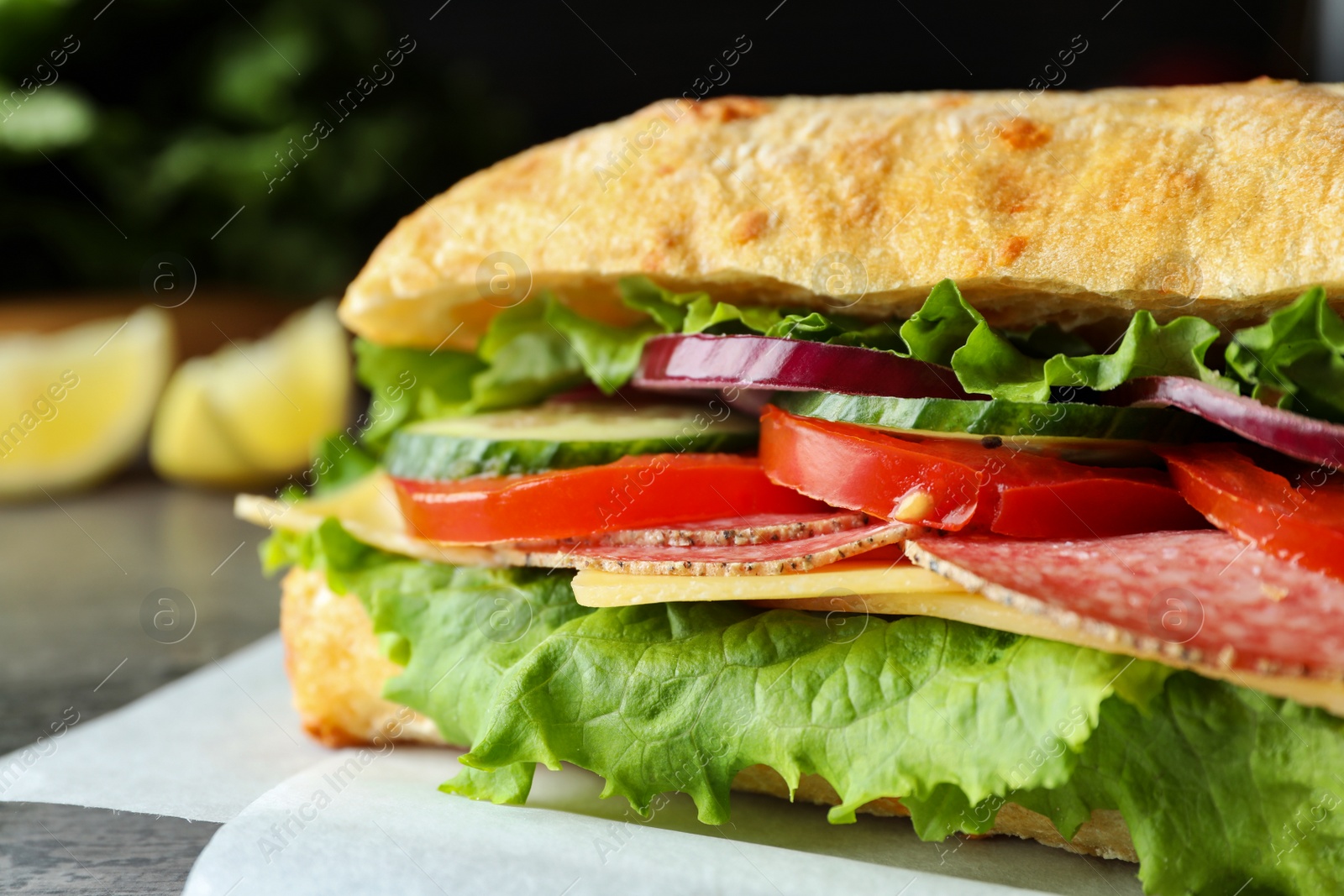 Photo of Delicious sandwich with fresh vegetables and salami on grey table, closeup