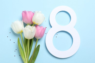 Photo of 8th of March greeting card design with paper number eight and beautiful flowers on light blue background, flat lay. International Women's day