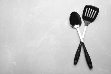 Different kitchen utensils on grey background, top view with space for text