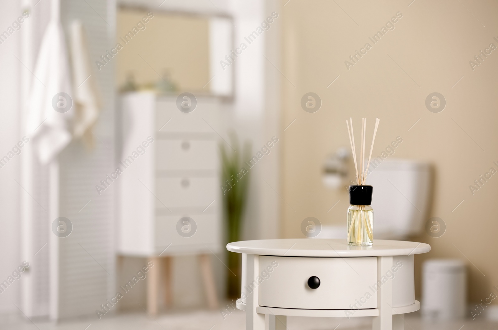 Photo of Aromatic reed air freshener on table against blurred background