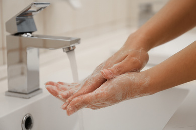 Photo of Woman washing hands with antiseptic soap in bathroom, closeup. Virus prevention