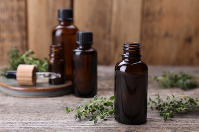 Photo of Thyme essential oil and fresh plant on wooden table, space for text