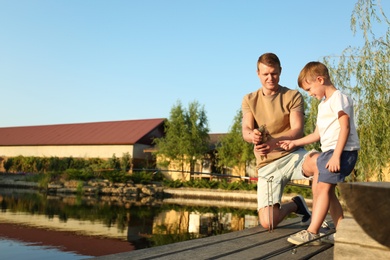 Dad and son fishing together on sunny day. Space for text