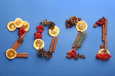 Photo of 2012 made of cranberries and Christmas decor on blue background, flat lay