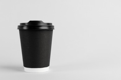 Photo of Black paper cup with plastic lid on light background, space for text. Coffee to go