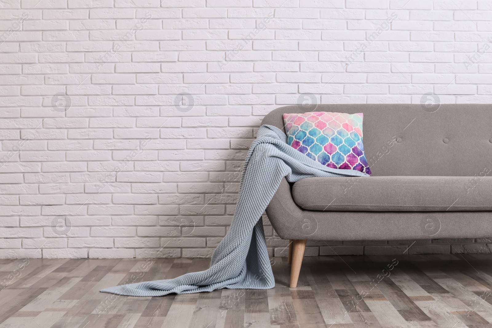 Photo of Minimalist living room interior with cozy sofa, pillow and plaid near brick wall. Space for text