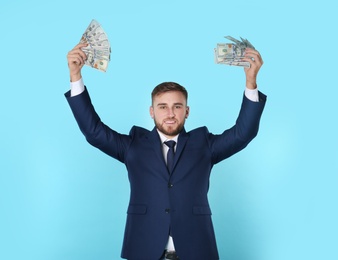 Portrait of happy young businessman with money on color background