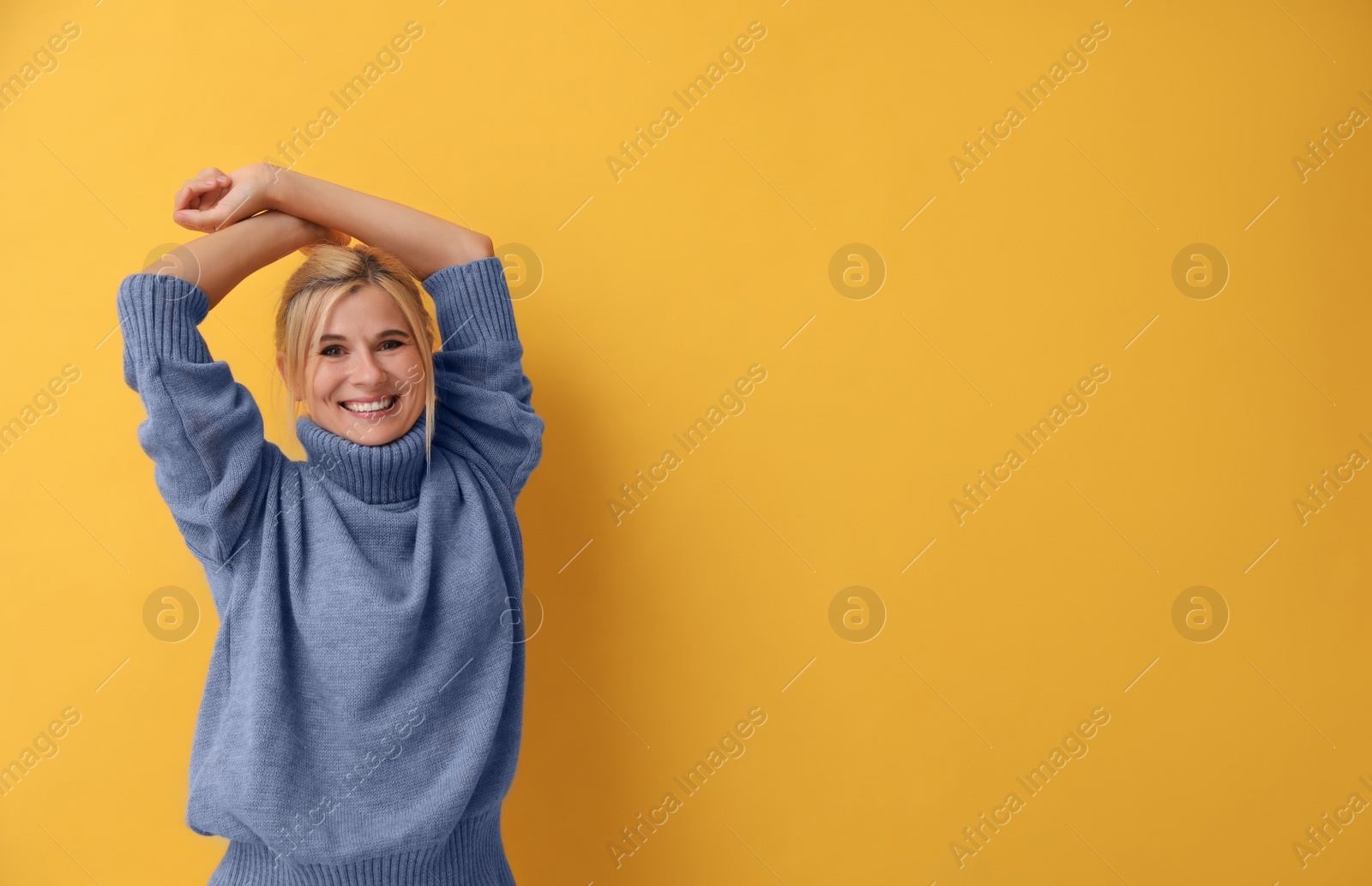 Photo of Happy woman in stylish sweater on yellow background. Space for text
