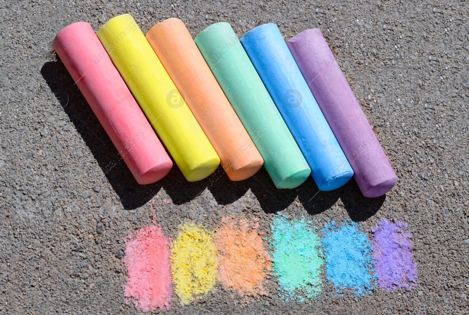 Photo of Colorful chalk sticks and strokes on asphalt outdoors, above view